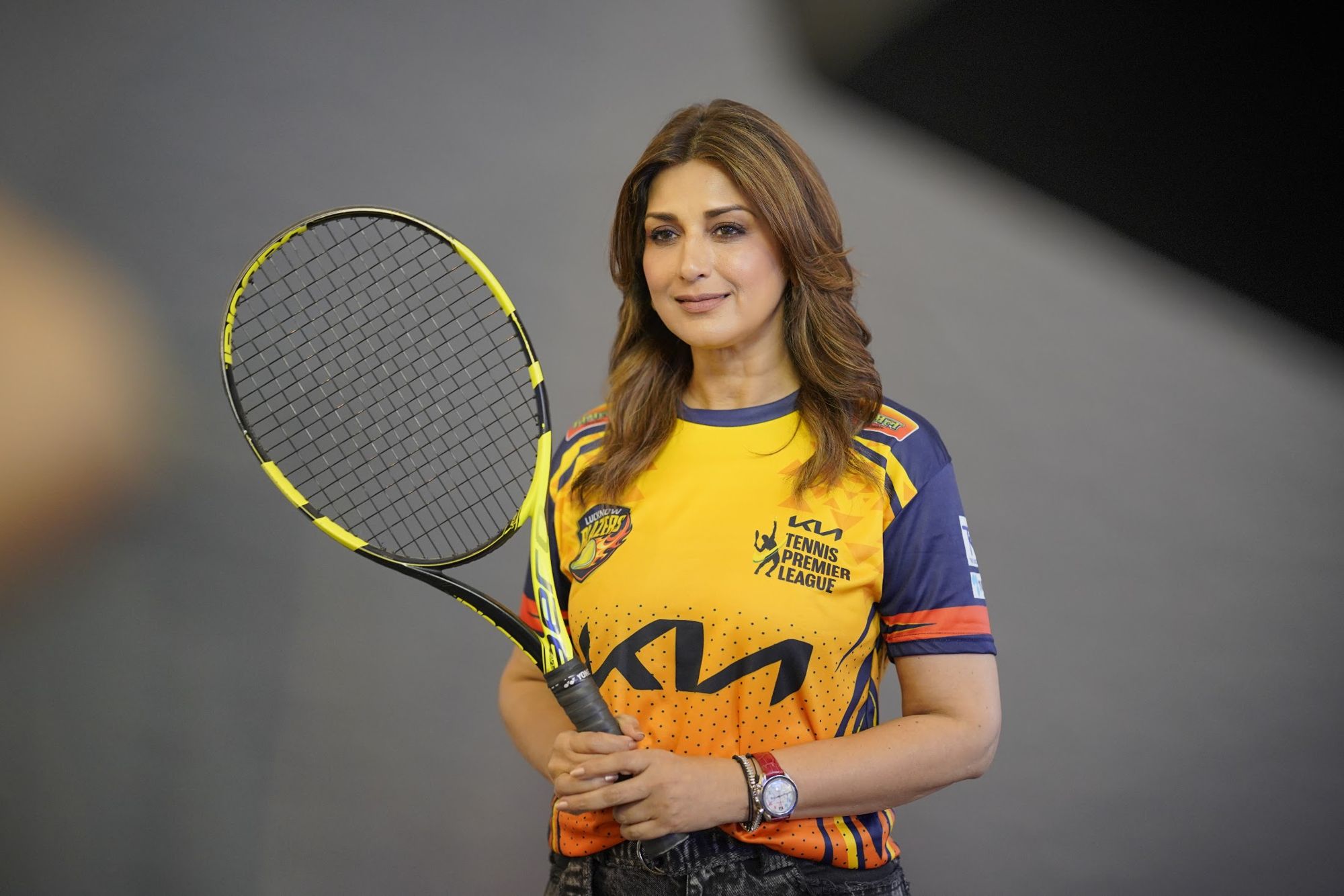 Sonali Bendre in the new Lucknow Blazers Season 8 jersey, holding a tennis racket